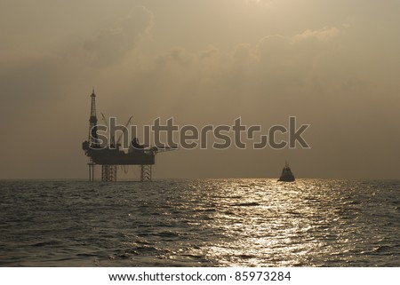 Oil rig with standby boat in the ocean