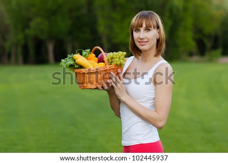 Young sportive woman with basket of fruits