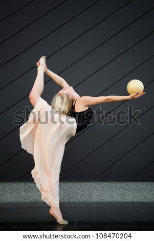 Beautiful blonde girl dancing with ball outdoor