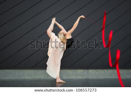 Young girl doing rhythmic gymnastics exercises with ribbon outdoor