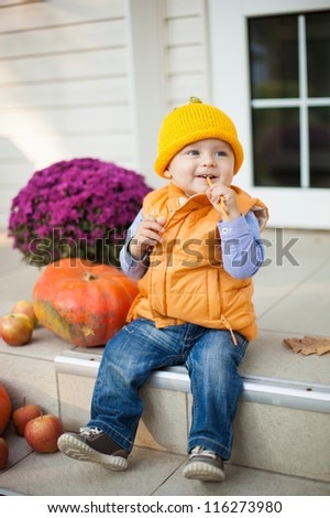 Happy little child sitting with  on house porch on halloween
