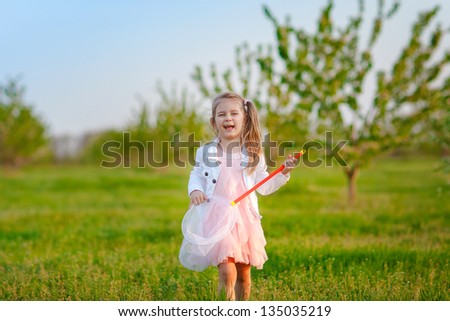 Happy little girl catching butterfly at sunny summer day