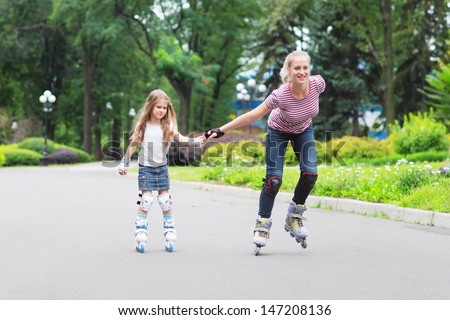 Girl beginner in roller skates with mom