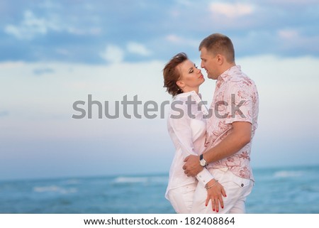 Young couple in love, attractive man and woman enjoying romantic evening walk on the beach