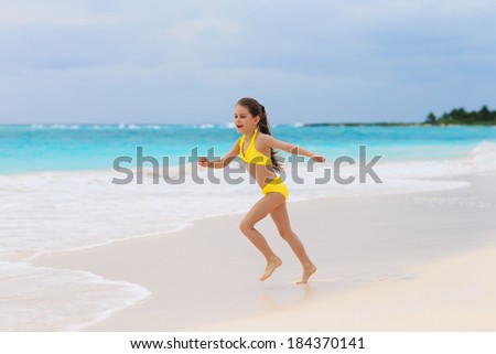 Little cute girl playing on the white sandy beach in Mexico