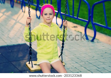 Cute girl having fun on a swing on summer day. Photo processed instagram style