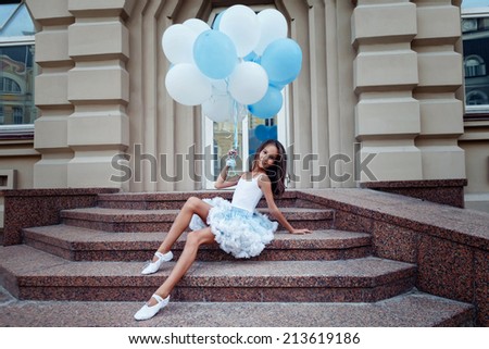 Adorable girl with blue and white balloons