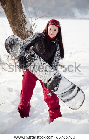 Sports woman with snowboard standing in winter park