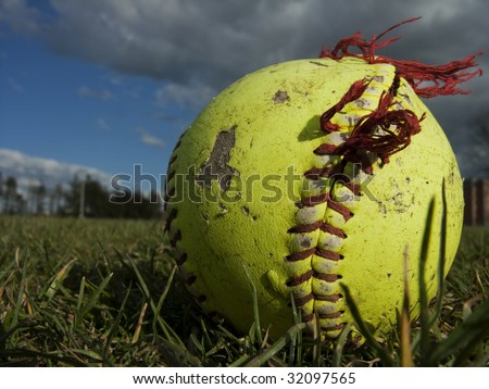Worn, frayed softball in grass