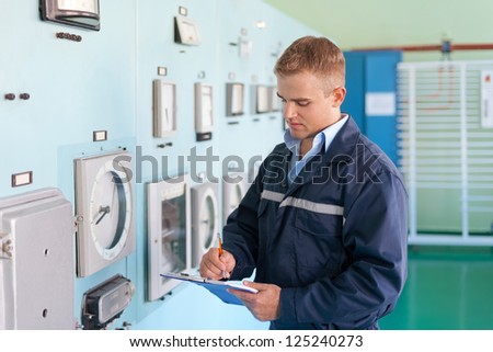 Portrait of young engineer taking notes at control room
