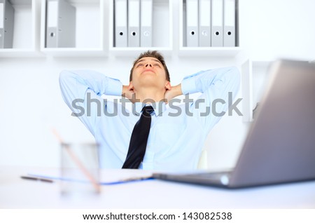 Relaxed young businessman at his workplace in bright office