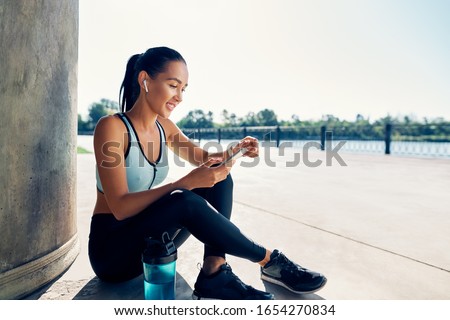 Happy fit woman holding smartphone and counts calories in sport app after running.  Sport, break concept  Сток-фото © 