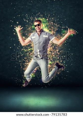 Jumping smiling young man on glowing abstract background