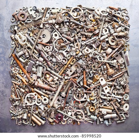 Square from assorted nuts and bolts on metal texture background