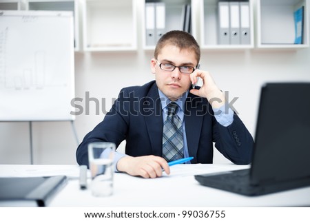 Young businessman talking on a cell phone at office