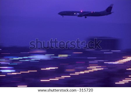 A jet approaches the runway at night for landing at the Los Angeles International Airport, USA. Panned shot.