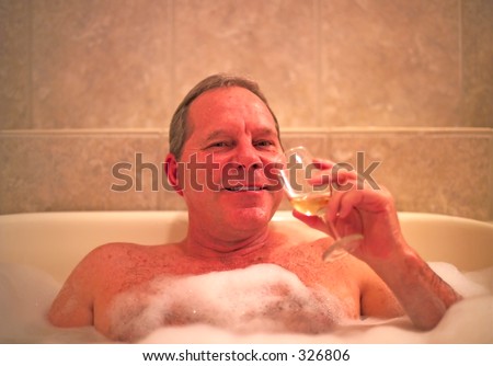A man with a glass of wine enjoys his relaxing jacuzzi bath in a resort hotel. Model released. (14MP camera)