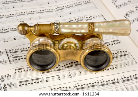 Antique opera glasses rest on a musical score. Focus=the camera right lens.12MP camera.