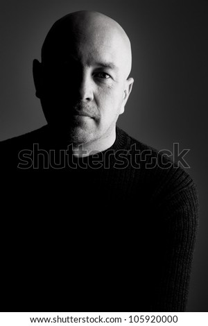 Bald man in black looking at the camera