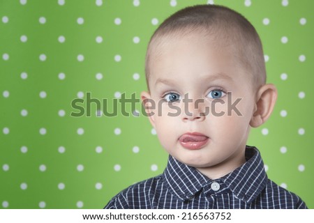 Adorable a little boy at the age of two in a shirt on light green background  looking at the camera close-up