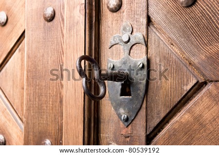 antique aged key in strong wooden door