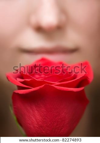 blurred portrait of woman is smelling red flower rose