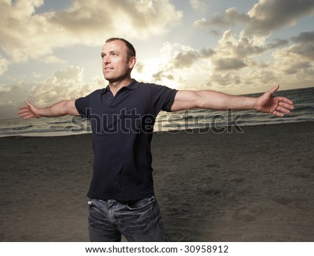 Handsome man with arms open during the sunset
