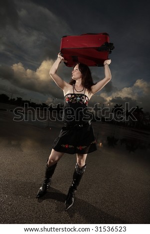 Woman raising a suitcase over her head