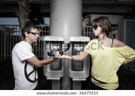 Couple passing the pay phone to each other