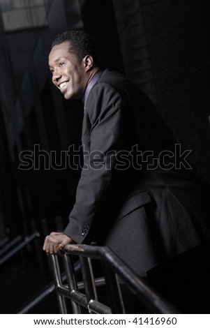 Young businessman smiling and leaning on a building rail