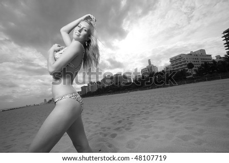 Black and white image of a young woman in a bikini on the beach