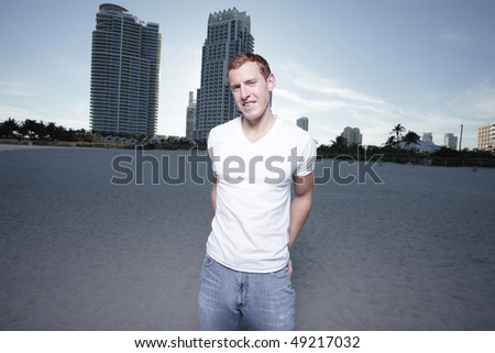 Man posing on the beach with his hands in his back pockets