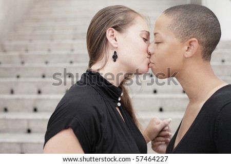 Two young women holding hands and kissing
