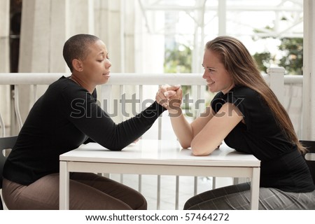Two young women arm wrestling