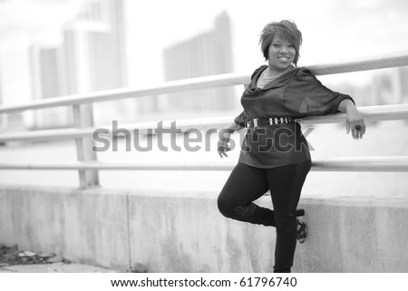 Black and white image of a young woman leaning on a guard rail