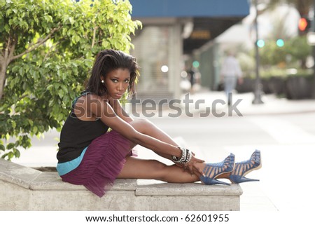 Attractive young woman sitting on a ledge in the city