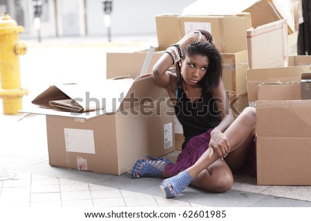 Young woman sitting next to empty boxes in the city