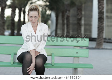 Woman sitting on a green bus stop bench