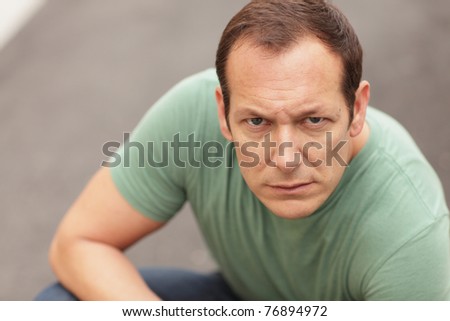Man crouching and making a mean facial expression