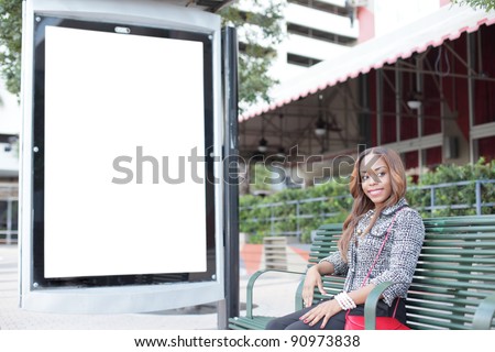 Woman sitting on a bus stop bench with a blank sign