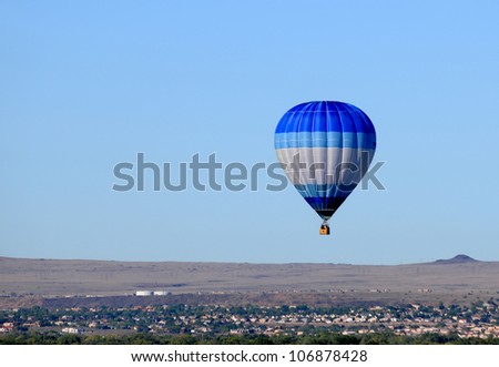 Blue hot air balloon floating over desert countryside