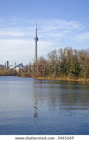 A view of the CN Tower from Centre Inland.  Skyline view is reflected in the water, and budding trees visible along right shoreline.
