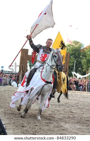 RIGA, LATVIA - AUGUST 21: Member of The Devils Horsemen stunt team riding horse and holding flag during Riga Festival on August 21, 2011 in Riga, Latvia