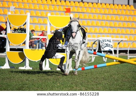 RIGA, LATVIA - SEPTEMBER 25 : An unidentified child falls from pony during Latvian Equestrian Federation cup in pony riding on September 25, 2011 in Riga, Latvia.