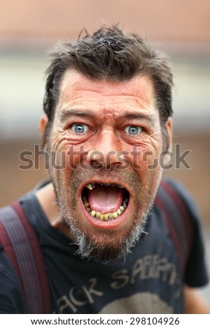 LONDON, UK - JULY 19: Insane homeless man is doing angry face expression in Twickenham on July 19, 2015