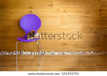 Purple chair with opened book next wooden wall / modern interior