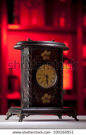 Vintage wooden clock standing on a table with beautiful dark red background