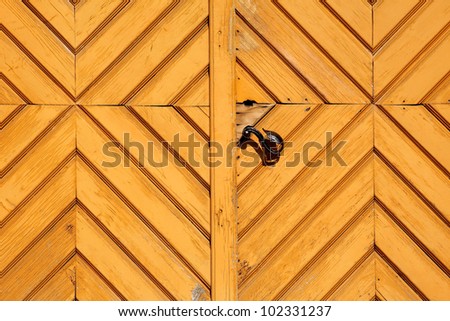 Detail of knot on a yellow old wooden house gate with unique pattern