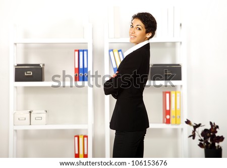 Pretty young business brunette girl posing and smiling in her office