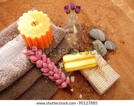 Soaps, candles, rocks, three towels and floral elements on a brown towel